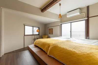 a bedroom with a bed with a yellow blanket at \u548c\u6c17\u4f1a\u3005\u690e\u540d\u753a Wakiaiai Shiinamachi in Tokyo