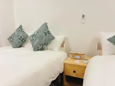 a room with two beds and a night stand at \u6696\u71c8 DANTO inn 2F in Tokyo