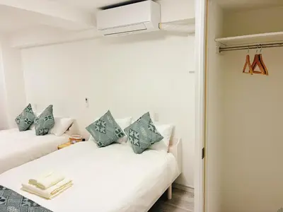 a bedroom with two white beds with blue pillows at \u6696\u71c8 DANTO inn 2F in Tokyo