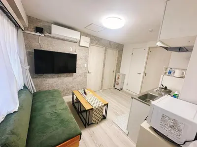a living room with a couch and a tv on a wall at \u6696\u71c8 DANTO inn 2F in Tokyo