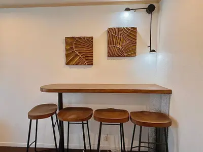 a bar with four stools under a counter with paintings at \u6c60\u888b\u5168\u65b0\u72ec\u7acb3\u5c42\u522b\u5885 3\u5ba41\u53851\u6d74\u5ba42\u536b\u751f\u95f4 \u6700\u59278\u4eba max 8P \u8f66\u7ad98\u5206\u949f 8mins to ST \u94f6\u5ea7 \u65b0\u5bbf \u6d89\u8c37 \u6c60\u888b \u4e1c\u4eac\u76f4\u901a in Tokyo