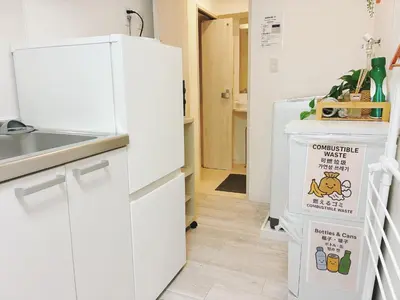 a kitchen with white cabinets and a refrigerator at \u6696\u71c8 DANTO inn 1F in Tokyo