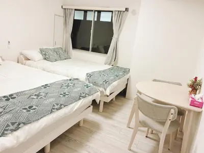 a room with two beds and a table and a desk at \u6696\u71c8 DANTO inn 1F in Tokyo