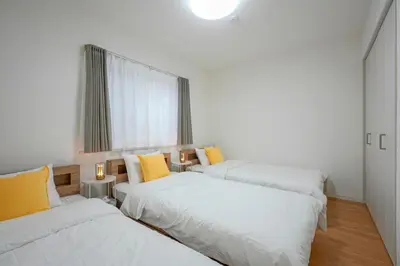 three beds in a room with yellow pillows at BT House Nakano3-3min Shinjuku 15min Shibuya-Modern 2BR-Convenient access to airports in Tokyo