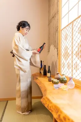 a woman in a kimono standing next to a table with wine bottles at sumica\u6d45\u8349\u82b1\u9ce5 in Tokyo