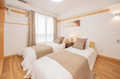 two beds in a room with a window at Mi-HOTEL SHINOTSUKA in Tokyo