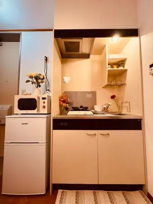 a small kitchen with a microwave and a refrigerator at Louis House\u897f\u65b0\u5bbf in Tokyo