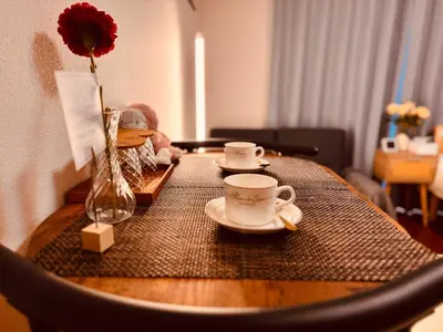 a table with two cups and a vase with a flower at Louis House\u897f\u65b0\u5bbf in Tokyo