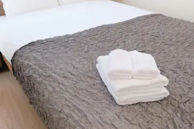a pile of white towels sitting on a bed at monthly EveryNet SHINJUKU II in Tokyo