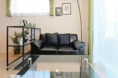 a black leather couch in a living room with a glass table at monthly EveryNet SHINJUKU II in Tokyo