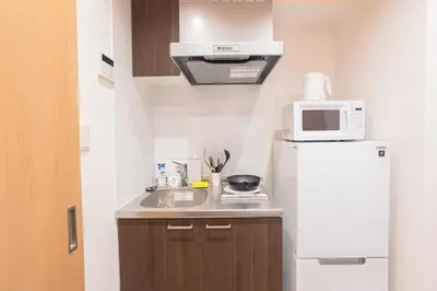 a small kitchen with a white refrigerator and a microwave at \u9ad8\u7530\u99ac\u5834\u99c5\u597d\u30a2\u30af\u30bb\u30b9 \u4ea4\u901a\u4fbf\u5229 \u89b3\u5149 \u30b7\u30e7\u30c3\u30d4\u30f3\u30b0 \u30b0\u30eb\u30e1\u3092\u4e00\u65e5\u3067 \u65e9\u7a32\u7530\u30a8\u30ea\u30a2\u3082\u8fd1\u3044 in Tokyo
