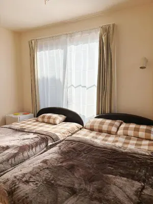 two beds in a room with a window at Aki House\u5c45\u4f4f\u578b\u6c11\u6cca\u5c0f\u5ca9\u99c5\u307e\u3067\u9001\u8fce\u3042\u308a in Tokyo
