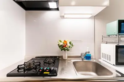 a kitchen with a stove and a sink with a vase of flowers at Shinagawa Tokyo - Great access to Bullet Train and Haneda in Tokyo