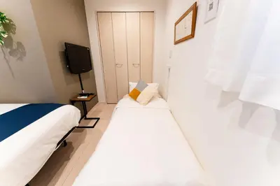 two beds in a small room with a tv at Shinagawa Tokyo - Great access to Bullet Train and Haneda in Tokyo