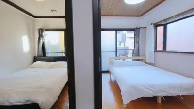 two beds in a room with two windows at Shinjuku 2bed rooms sunny apart ment#2\u5ba41\u5385\u9633\u5149\u516c\u5bd3#\u9ad8\u901f\u65e0\u9650\u5236\u7f51\u8def2#1 in Tokyo