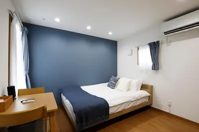 a bedroom with a blue wall with a bed and a desk at LIFE TOWN Nishiarai II in Tokyo