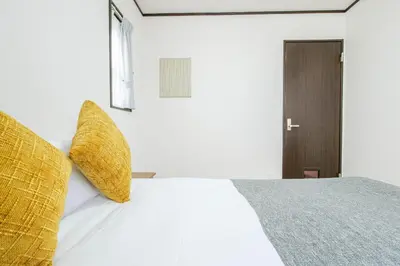 a bedroom with a white bed with yellow pillows at \u5927\u5cf6Villa in Tokyo