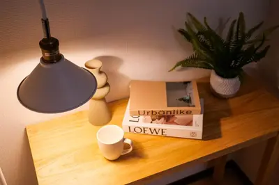 a table with a lamp a book and a cup and a plant at \u5927\u5cf6Villa in Tokyo