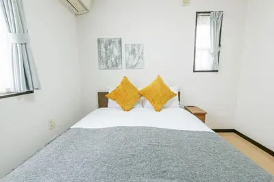 a bedroom with a white bed with yellow pillows at \u5927\u5cf6Villa in Tokyo