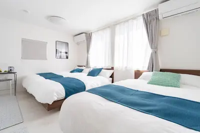 a bedroom with two beds and a flat screen tv at Shibuya Base in Tokyo
