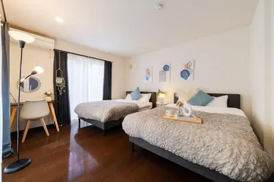 a hotel room with two beds and a desk and a table at GC TOKYO Shinjuku-Ochiai in Tokyo