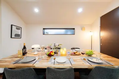a large wooden table with chairs and plates and wine glasses at GC TOKYO Shinjuku-Ochiai in Tokyo