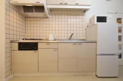 a kitchen with wooden cabinets and a white refrigerator at memento 20minutes from Haneda Airport 10minute walk from JR Kamata Station in Tokyo