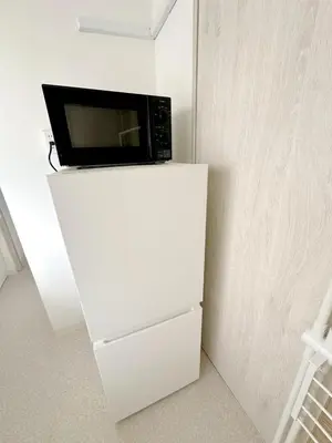 a microwave sitting on top of a white refrigerator at \u6696\u71c8 DANTO inn 3F in Tokyo