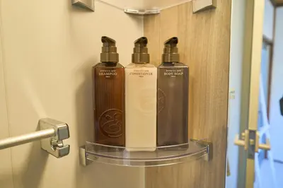 three bottles of shampoo on a shelf in a bathroom at Kita-Senju House in Tokyo