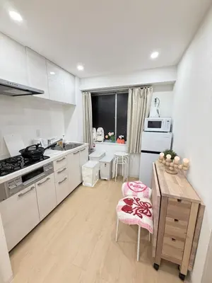 a kitchen with white cabinets and a wooden table at PUZZLE hotel 401 in Tokyo
