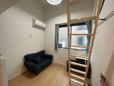 a living room with a ladder and a chair and a window at 5 min to Shinjuku, 1 min walk to Shinnakano Station, Room 102 in Tokyo