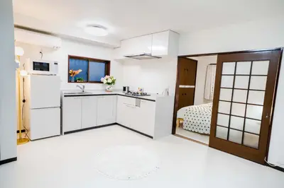 a kitchen with white cabinets and a refrigerator at 102Room,Free parking just a 7-minute walk from Koiwa tram stop This spacious 75-square-meter flats features two large bedrooms and can accommodate up to seven guests in Tokyo