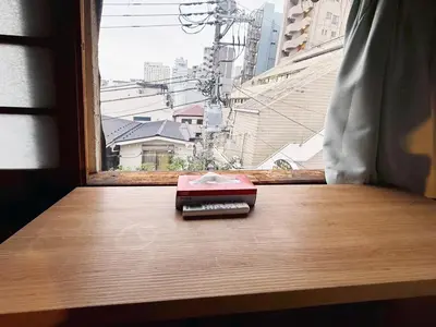 a book sitting on a table in front of a window at Male-only dormitory Tokyo House INN in Tokyo