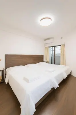 a bedroom with a large white bed with a wooden headboard at Ojihoncho301 Triple Room in Tokyo