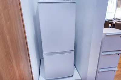 a white refrigerator in a kitchen next to a door at Shinjuku Nakai House in Tokyo