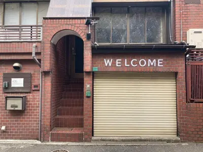 a brick building with two garage doors and a welcome sign at Newly Opened \u6c60\u888b\u30c6\u30e9\u30b9\u30cf\u30a6\u30b9B in Tokyo