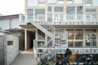 a person sitting at a table in front of a building at monthly U Place Shimokitazawa in Tokyo