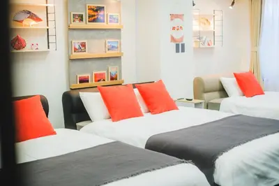 three beds in a room with orange pillows at Stay Chill Toranomon in Tokyo