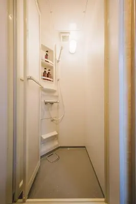 a small walk in shower in a white bathroom at Stay Chill Toranomon in Tokyo