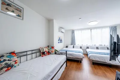 a room with three beds and a flat screen tv at SHOGUN HOTEL HORIKIRi in Tokyo