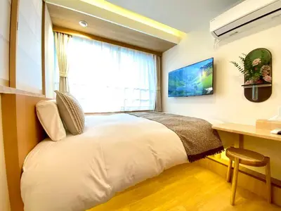 a bedroom with a bed and a desk and a window at H-Tokyo Simple and Warm Rooms in Tokyo