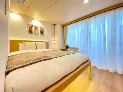 a bedroom with a large bed and a large window at H-Tokyo Simple and Warm Rooms in Tokyo