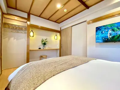 a bedroom with a bed and a tv on the wall at H-Tokyo Simple and Warm Rooms in Tokyo