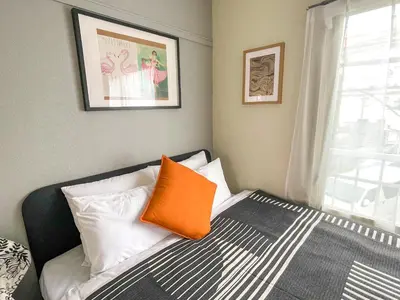 a bedroom with a bed with an orange pillow on it at AAt Hotel \u30a2\u30fc\u30d0\u30f3\u30cf\u30a4\u30c4\u5c0f\u83c5201 in Tokyo