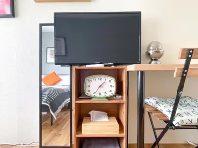 a television on a stand with a clock on it at AAt Hotel \u30a2\u30fc\u30d0\u30f3\u30cf\u30a4\u30c4\u5c0f\u83c5201 in Tokyo