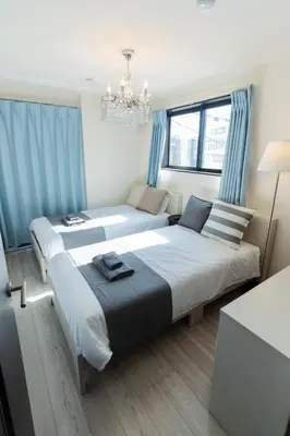 a bedroom with two beds with blue curtains and a chandelier at Tokyo Skytree 201 Elegance Blue Twin Room with Bath and WC in Tokyo