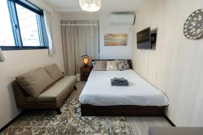 a small bedroom with a bed and a couch at Tokyo Skytree 302 Bali-Style Double Bath & WC in Tokyo