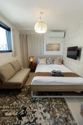 a bedroom with a bed and a couch and a tv at Tokyo Skytree 402 Bali-Style Double bed Bath & WC in Tokyo