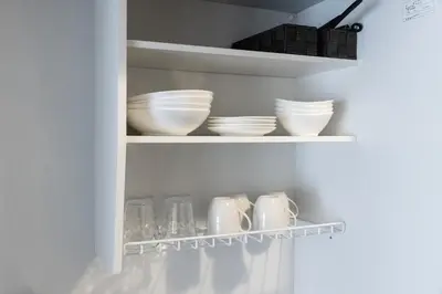 a white cabinet with bowls and plates and cups at Shibuya Crossing 5mins walk COZY BRIGHT COMFY PAD 35sqm in Tokyo
