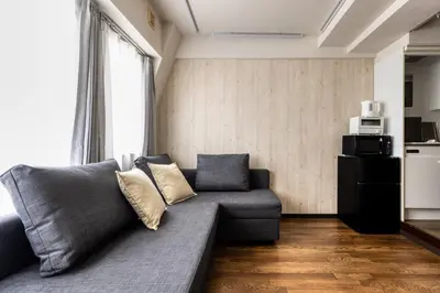 a living room with a gray couch and a kitchen at Shibuya Crossing 5mins walk COZY BRIGHT COMFY PAD 35sqm in Tokyo